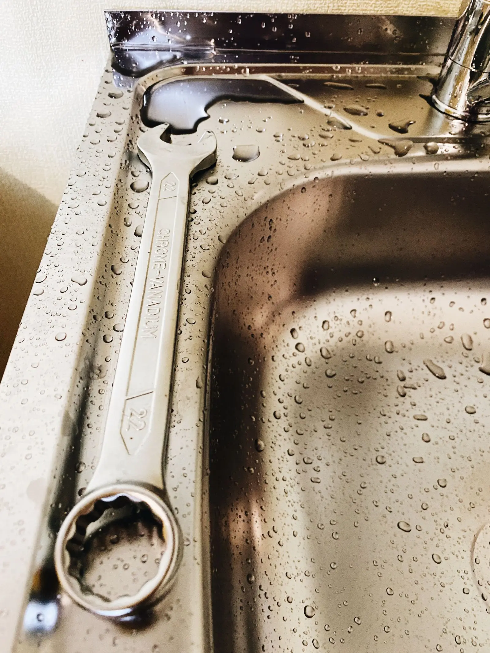Wrench resting on a wet stainless steel sink